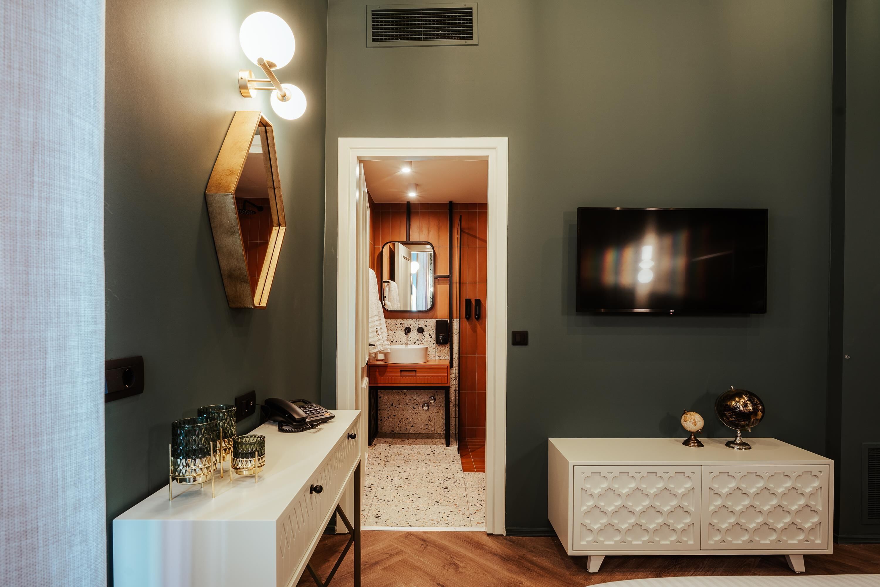 A modern bathroom with a vanity, mirror, and a television mounted on the wall.