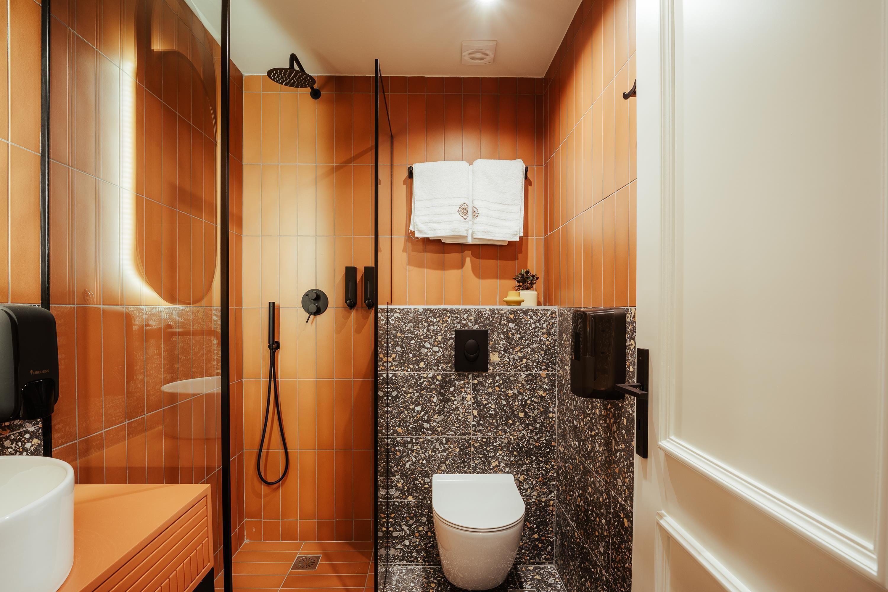 Un baño pequeño con ducha, inodoro y lavamanos.