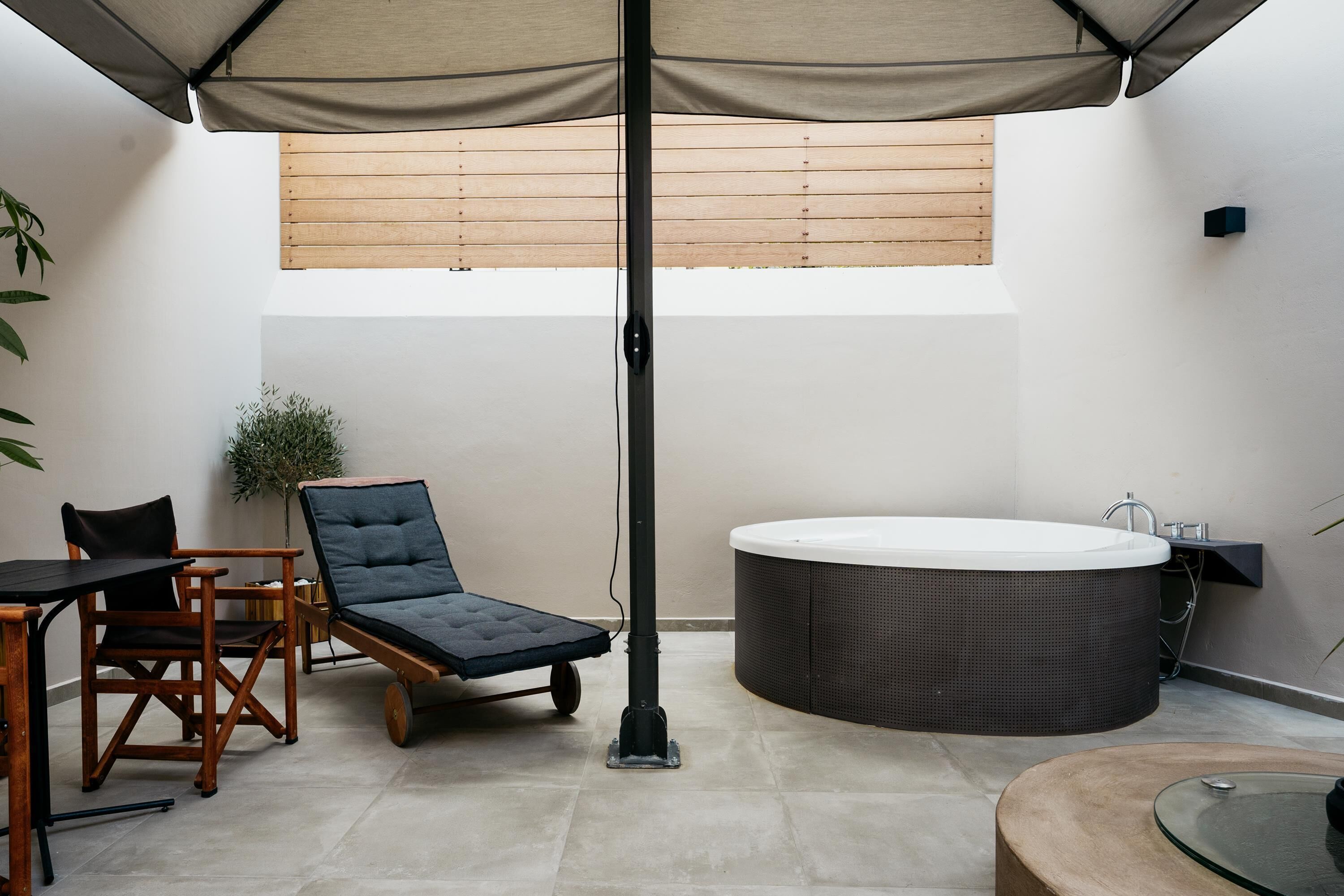 A modern outdoor seating area with a lounge chair, a table, and a glass-top table.