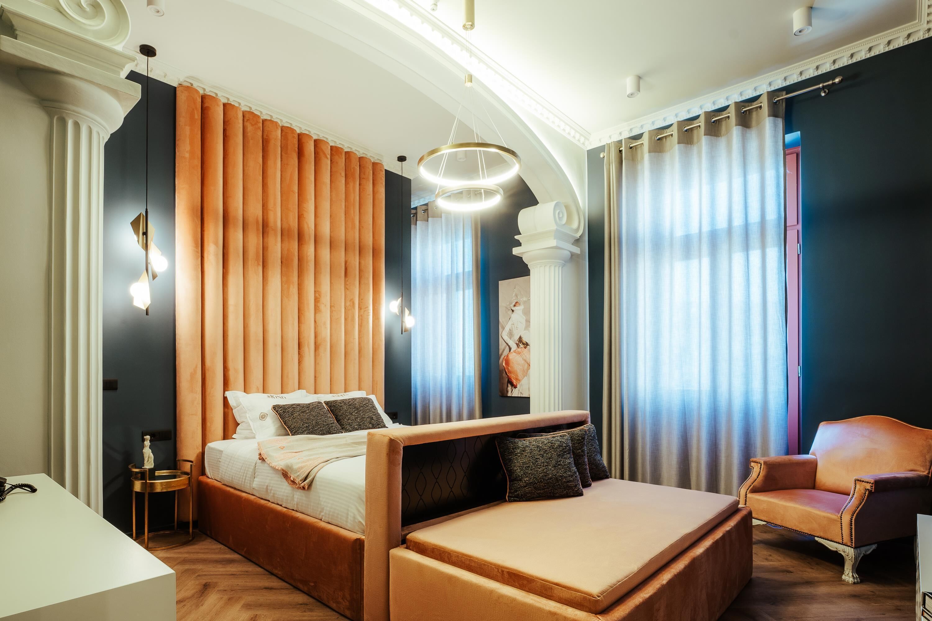 Ein modernes Schlafzimmer mit einem großen Bett, einer Liege, einem Schreibtisch und einem Sessel.