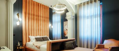A modern bedroom with a large bed, a chaise lounge, a desk, and a chair.