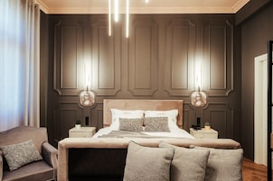 Un dormitorio con cama, mesitas de noche, una silla y una lámpara.