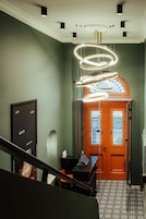 Un interior moderno con una escalera, una puerta de madera con paneles de vidrio y una lámpara de techo original.