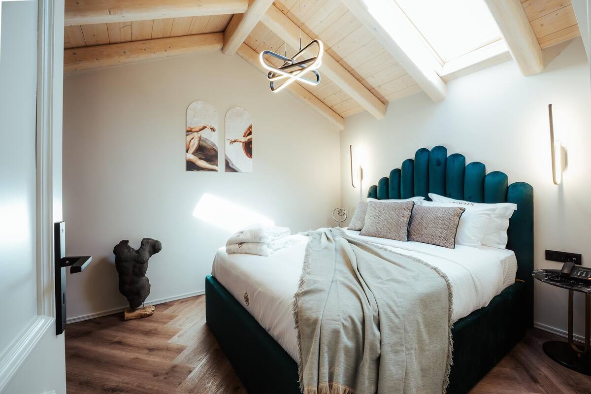 A bedroom with a bed, wooden ceiling, wall art, and a modern light fixture.