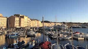 A marina with boats docked, buildings along the waterfront, and a clear sky.