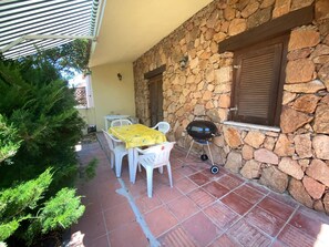 A patio with stone walls, a grill, and outdoor furniture.