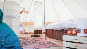 Ein Zeltinnenraum mit einem Bett, einem Hängesessel und einem Tisch mit Äpfeln.