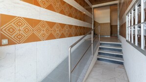 Un intérieur moderne avec des murs à motifs, un escalier en métal et un sol carrelé aux lignes épurées.