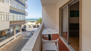 Un balcon avec vue sur la plage, une table et des chaises.