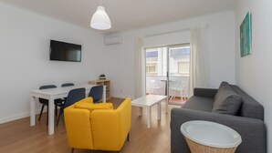 Un salon moderne avec un canapé gris, un fauteuil jaune et une table à manger blanche.