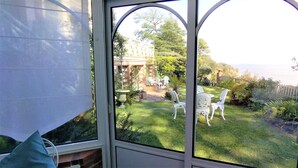 A conservatory with a view of a garden and a building in the background. - "Un Petit Coin de Paradis" (Saint-Nazaire)