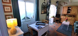 Ein gemütliches Wohnzimmer mit Tisch, Stühlen, einer Lampe, einem Bücherregal und einem Fernseher.