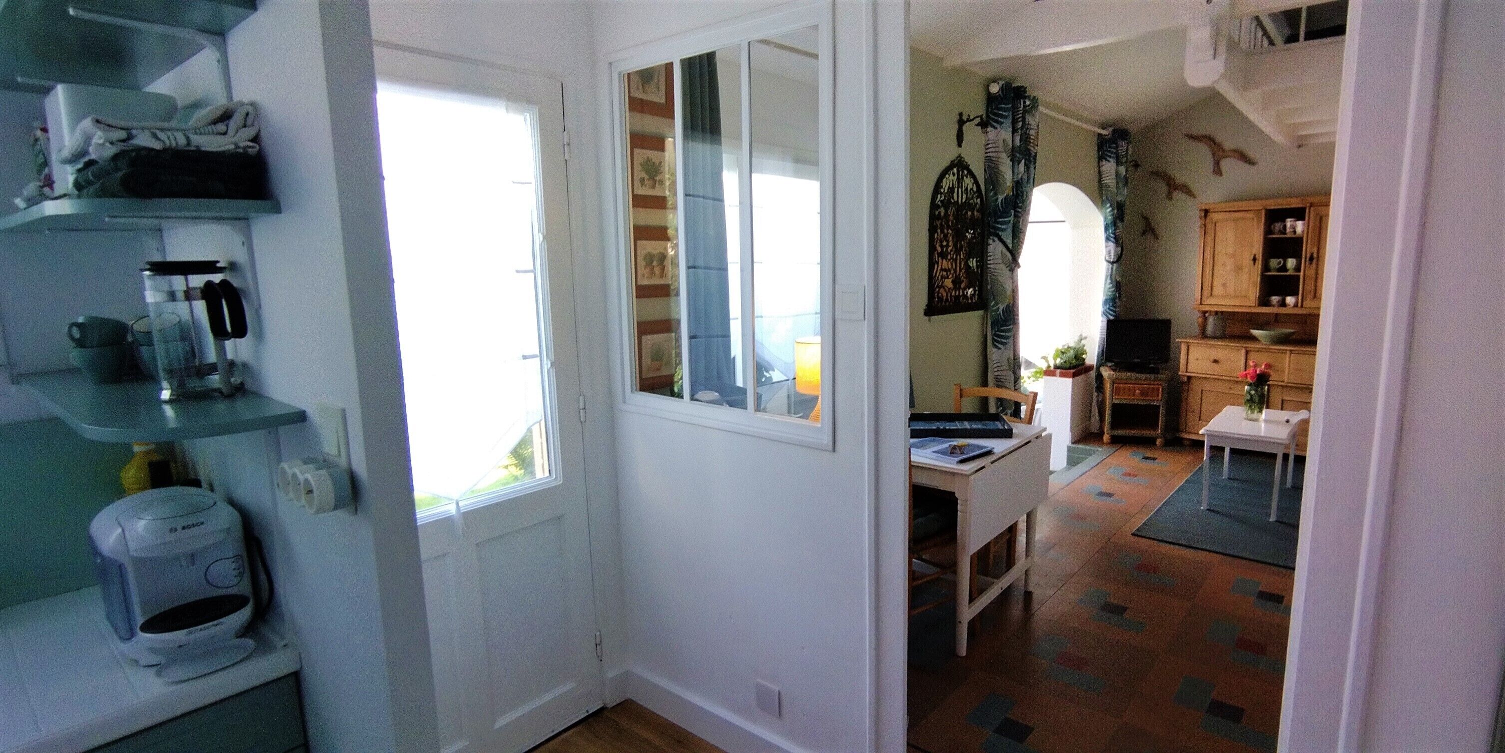 A compact kitchen with a coffee maker, a small table, and a window.