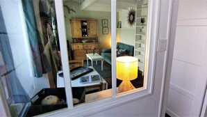 A room with a window, a table with a lamp, a chair, a sofa, and a cabinet. - "Un Petit Coin de Paradis" (Saint-Nazaire)