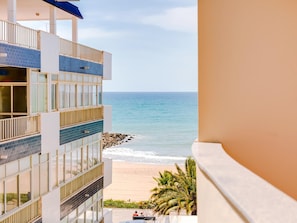 A multi-story hotel with balconies overlooking a beach.
