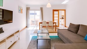 Ein modernes Wohnzimmer mit Sofa, Fernseher und einem Essbereich mit Stühlen und Tisch.