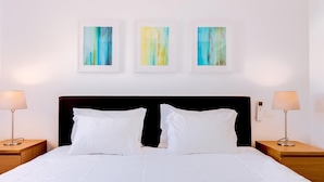 Ein Hotelzimmer mit einem großen Bett, zwei Nachttischen und drei abstrakten Bildern an der Wand.
