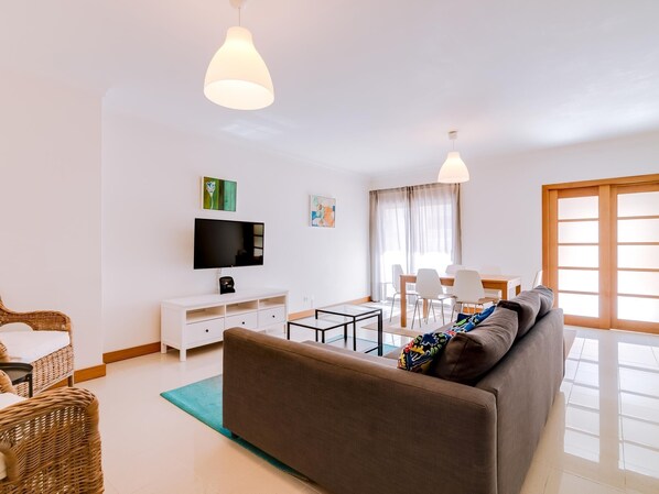 A modern living room with a sofa, TV, dining table, and chairs. - Completely new, with sea view (Quarteira)