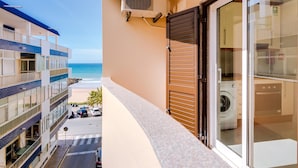 Ein Balkon mit Waschmaschine, Blick auf den Strand und einer Fujitsu-Klimaanlage.