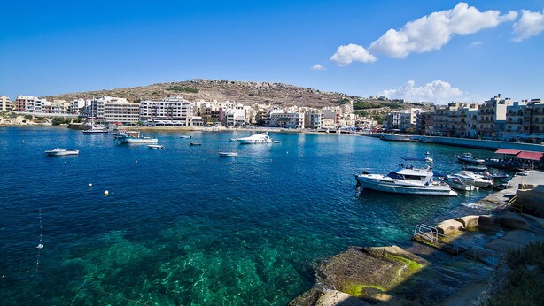 Une ville côtière aux eaux d’un bleu limpide, où l’on peut admirer des bateaux et des bâtiments le long de la côte.