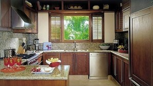 Une cuisine avec des meubles de rangement en bois, un plan de travail en granit, un lave-vaisselle et une fenêtre équipée de stores.