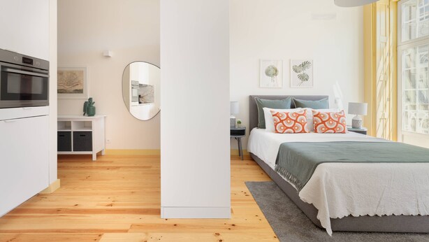 Une chambre moderne avec un lit, des tables de chevet, un miroir et une vue sur l’extérieur.