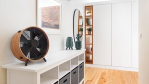 Une pièce moderne avec une console blanche, un grand ventilateur, une bibliothèque et une armoire.