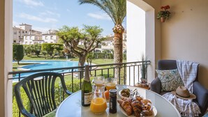 A balcony with a table set for breakfast, including croissants and juice, overlooking a swimming pool and greenery. - Avalon (Javea / Xàbia)