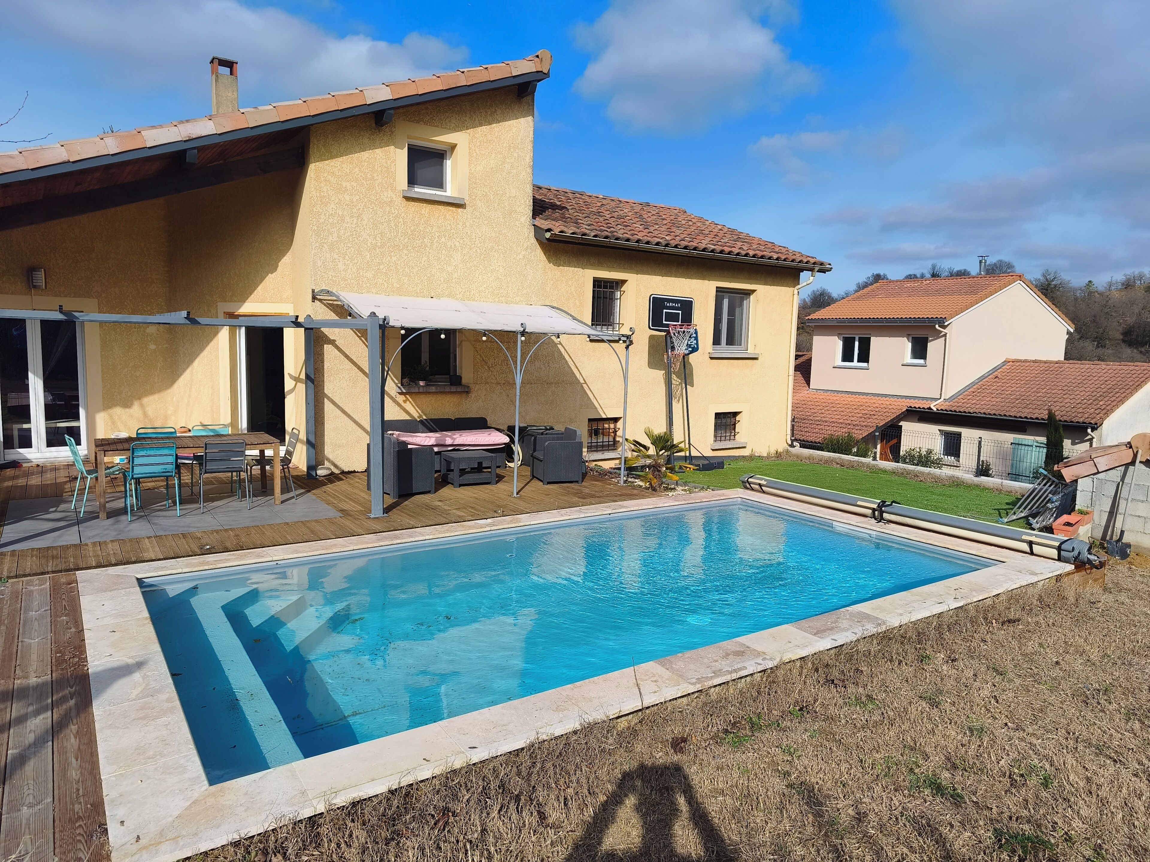 Um imóvel residencial com piscina, móveis de jardim e área de estar coberta ao ar livre.