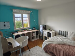 A bedroom with a desk, chair, bed, and storage units.