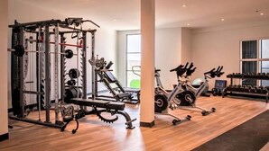 A spacious gym with a variety of equipment including a squat rack, dumbbells, and an exercise bike.