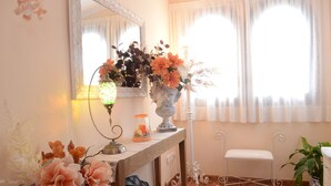 A room with a wooden console table, a mirror, a vase with flowers, a lamp, a chair, and a potted plant. - Villa Balneari Resort. Vacaciones en Familia y amigos Piscina Tenis Golf, Futbol (Rustical Balneario. Mont-roig del Camp)