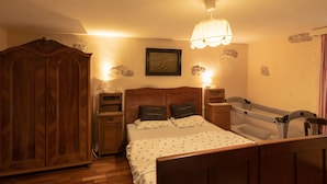 A bedroom with a wooden bed, bedside tables, a wardrobe, and a hanging light fixture. - Villa Nana (Dobrinj)