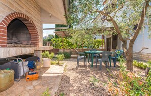 An outdoor patio with a brick oven, outdoor seating, and a garden area. - Apartment Domenico (Biograd)