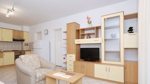 A modern kitchen with a sofa, a dining table, and a TV. - Apartment Emina (Sv. Filip i Jakov)