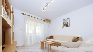 A living room with a sofa, a wooden table, and a TV. - Apartment Emina (Sv. Filip i Jakov)