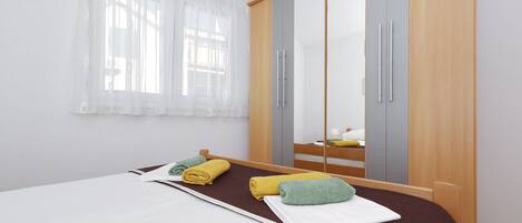 A hotel room with a bed, a wardrobe, and a window with curtains.