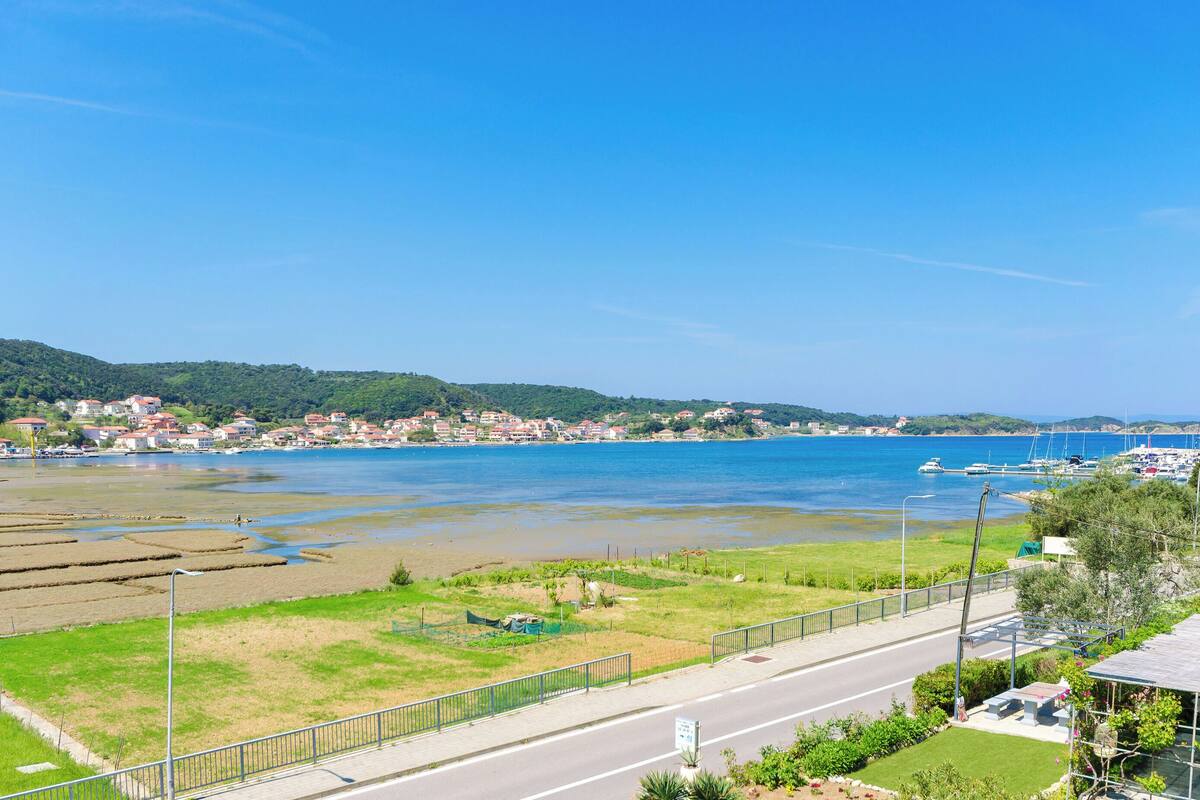 A coastal town with a clear view of the sea, a road, and residential buildings.