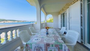 A balcony with a table set for two, overlooking a coastal view. - Apartment Marica (Supetarska Draga)