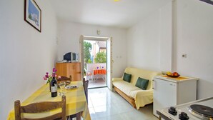 A compact living space with a dining area, kitchenette, and a sofa. - Apartments Iris (Rabac)
