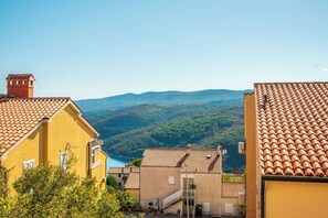 A yellow building with a red-tiled roof, a staircase, and a view of a valley.