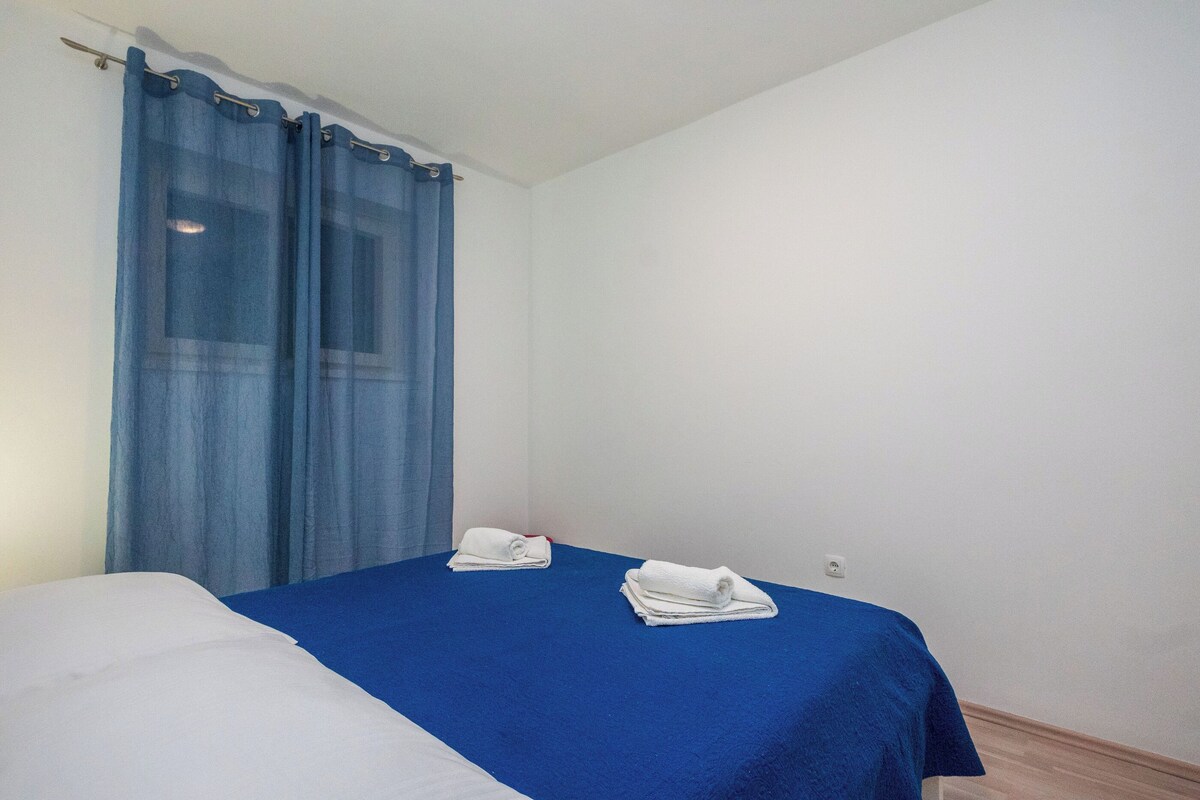 A simple room with a bed, a blue curtain, and two white towels.