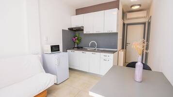 A compact kitchenette with a microwave, stove, sink, and cabinets.