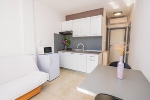 A compact kitchenette with a microwave, stove, sink, and cabinets. - Apartments Iris (Rabac)