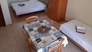 A small, tidy room with a bed, a table with a tablecloth, and a wardrobe. - Apartments Pavelic (Povile)