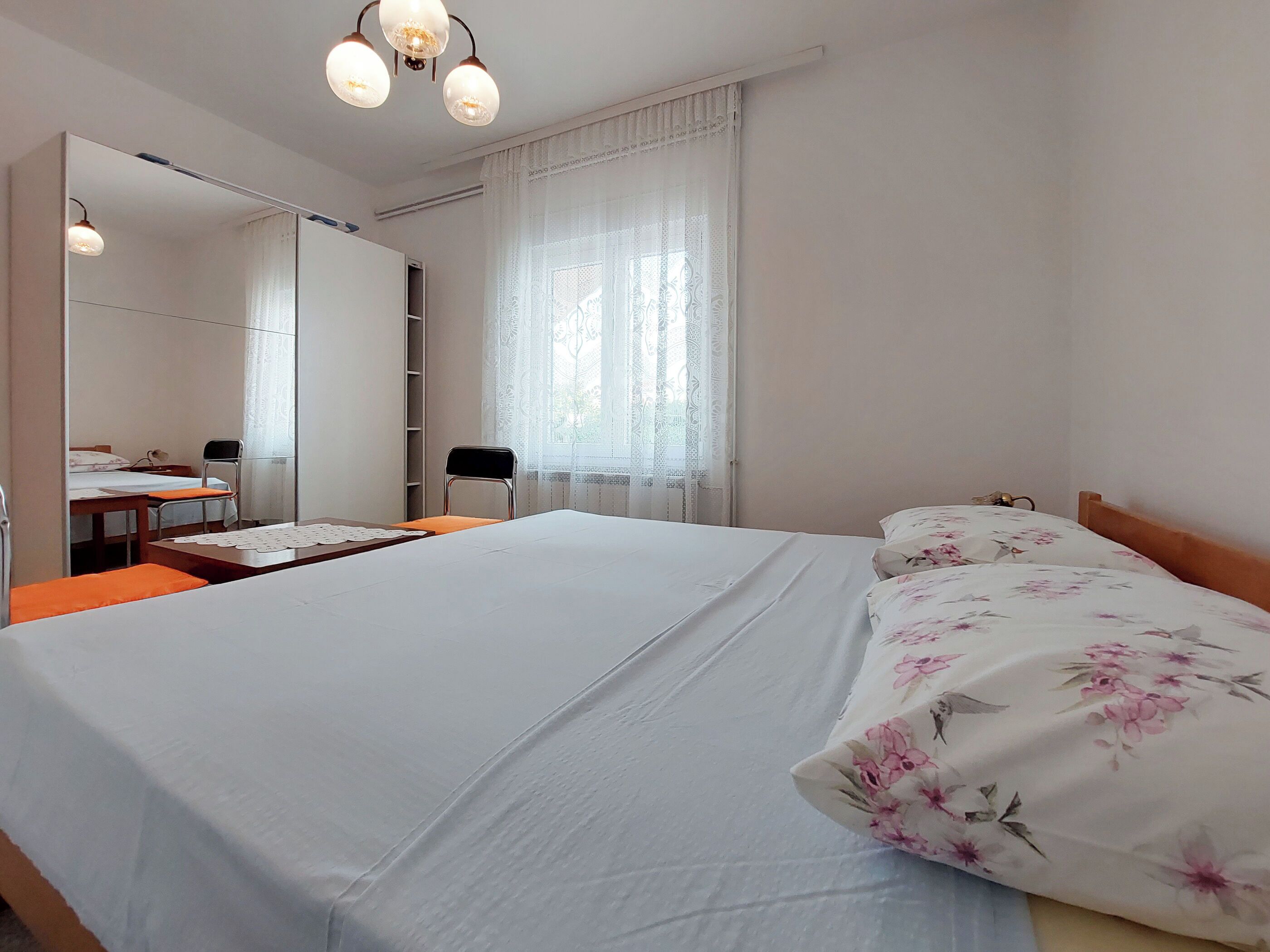 Een hotelkamer met een groot bed, een bureau, een stoel, een kledingkast en een raam met gordijnen.