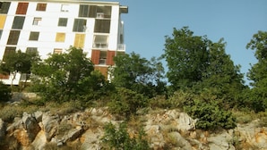 A multi-story building with balconies and a rocky terrain in the foreground. - Apartment Andela (Senj)