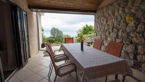 Un área de comedor al aire libre con mesa y sillas, un muro de piedra y vistas del paisaje.