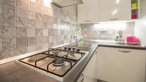 Una cocina moderna con estufa a gas, armarios blancos y salpicadero de azulejos.
