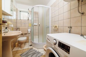 A bathroom with a toilet, sink, shower, and washing machine. - House Marija (Poljica)